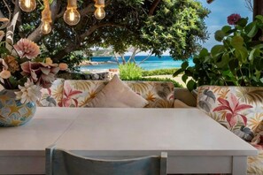 A dining area with a table, chairs, and a view of the sea. - Elite Collection Villa Pevero Acquamarina (Porto Cervo)