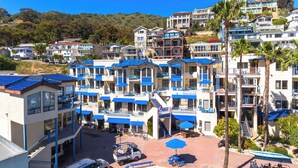 A multi-story hotel with balconies, a parking area, and a view of a hillside. - Charming Hideaway: 3 Family-Friendly Rooms, Near Catalina Island Museum (Avalon)