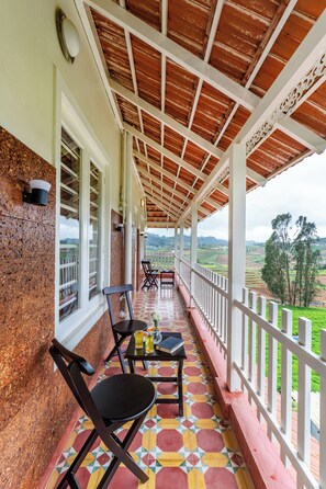 A covered outdoor area with chairs and tables, a view of the countryside, and a wooden ceiling. - Alaya Stays Mihirikas Nirvana 5-BHK (Ooty)