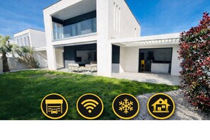 Une maison moderne à deux étages, dotée d’un garage, d’une connexion Wi-Fi, d’un espace extérieur couvert et d’un jardin.