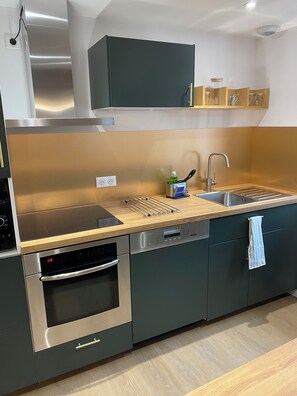 A modern kitchen with stainless steel appliances, a wooden countertop, and a built-in dishwasher. - Charming gite in the heart of Combleux, a seafaring village near Orléans (Combleux)