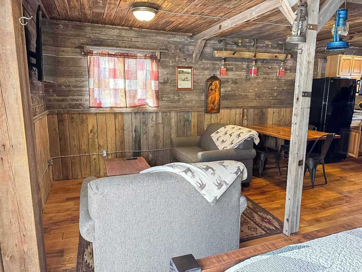L’intérieur d’un chalet rustique, avec un canapé, une table à manger et des chaises.