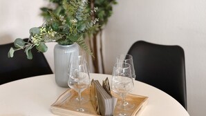 Une table avec deux verres à vin, un vase avec des plantes vertes et un plateau sur lequel se trouve un livre.