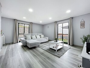 Ein modernes Wohnzimmer mit einem grauen Sofa, einem Couchtisch und Blick ins Freie.