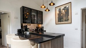 A modern kitchen with a black countertop, stainless steel appliances, and pendant lighting. - Tranquil cottage stay with fireplace and pond (Oswestry)