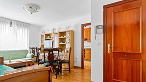 A room with a wooden bed, a dining table with chairs, a sofa, a wooden cabinet, and a door. - Apartment 'Carmina El Fondon 3' with Balcony and Wi-Fi (Cangas de Onís)