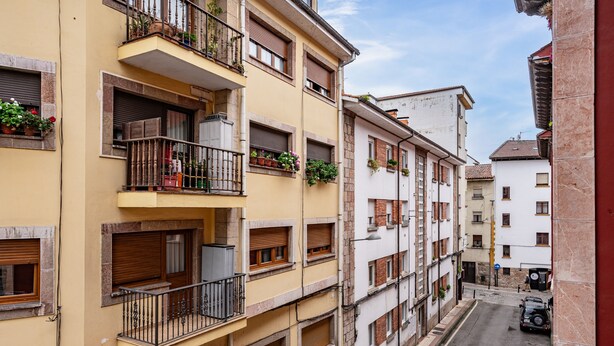 A multi-story building with balconies, windows with shutters, and a narrow street. - Apartment 'Carmina El Fondon 3' with Balcony and Wi-Fi (Cangas de Onís)