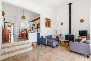 Ein Wohnzimmer mit einer Couch, einem Fernseher, einem Kamin und einem Essbereich mit Stühlen und einem Tisch.