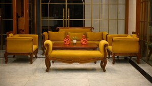 Une pièce comprenant un canapé, deux fauteuils, une table basse en bois et un miroir.