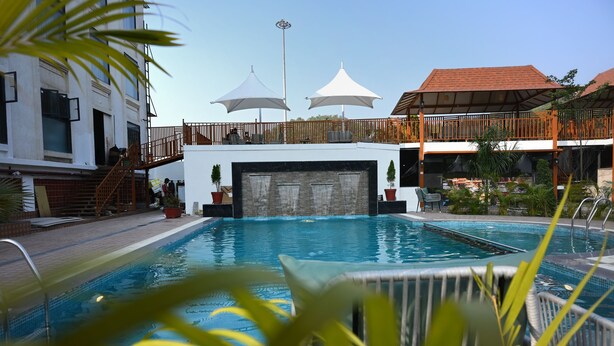 Une piscine avec une terrasse en bois, des parasols et un bâtiment doté d’un balcon.