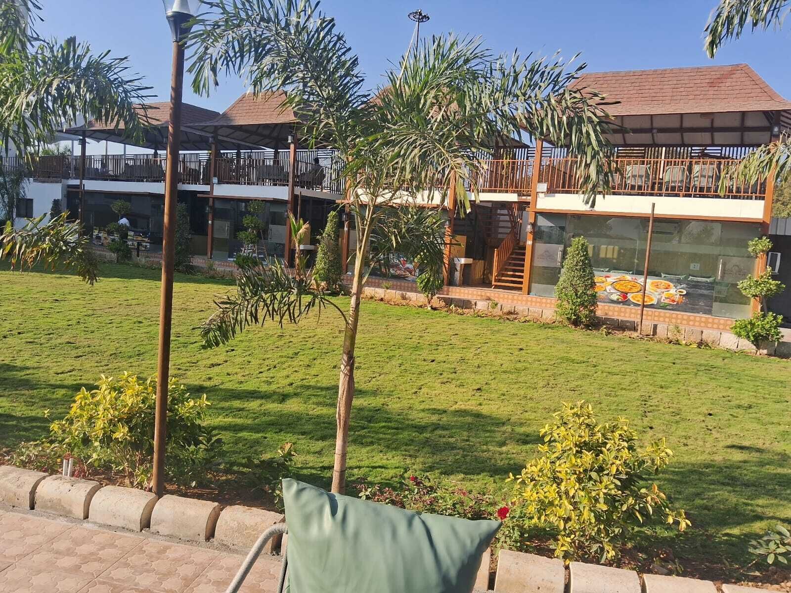 Un hotel con una zona de estar exterior cubierta, un césped y vistas de los edificios circundantes.