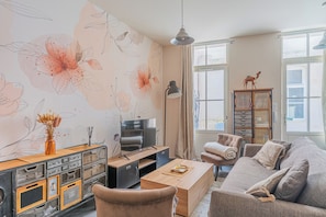 A living room with a sofa, coffee table, TV, and a cabinet with drawers. - La Rochelle Downtown Market, Wi-Fi (La Rochelle)