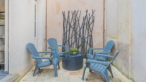 A small outdoor seating area with four chairs and a round table, surrounded by a low wall and a decorative metal fence. - Nid du marché downtown La Rochelle, wifi (La Rochelle)
