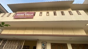 Un edificio con un letrero que dice 'ROSE VILLA HOME STAY' y una ventana con un diseño decorativo.