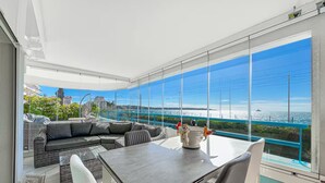 Un balcone moderno con un tavolo da pranzo, sedie e un divano.