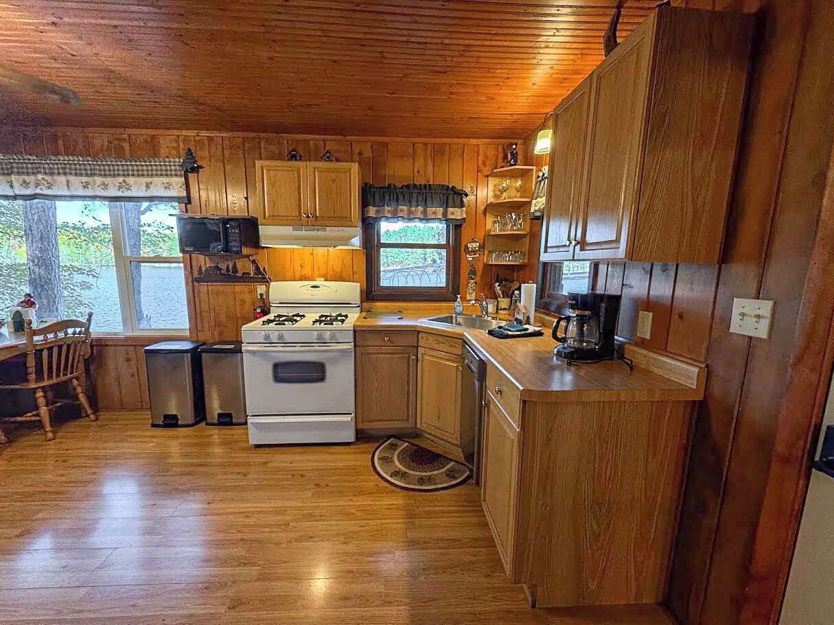 Une cuisine de taille réduite, dotée de meubles en bois, d’une cuisinière, d’un four à micro-ondes et d’un évier.