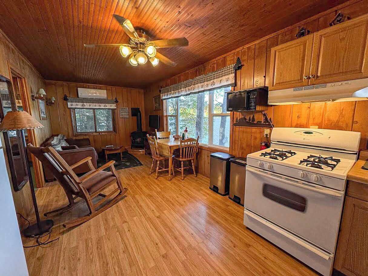 A cozy cabin interior with a dining area, kitchen, and a rocking chair.