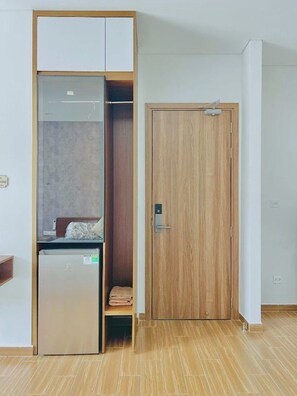 Une chambre compacte comprenant un placard, un petit lit et un mini-réfrigérateur encastré.