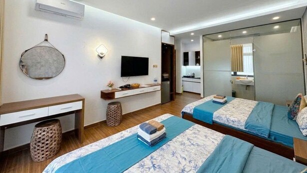 Habitación de hotel moderna con dos camas, un escritorio, un televisor y un espejo.
