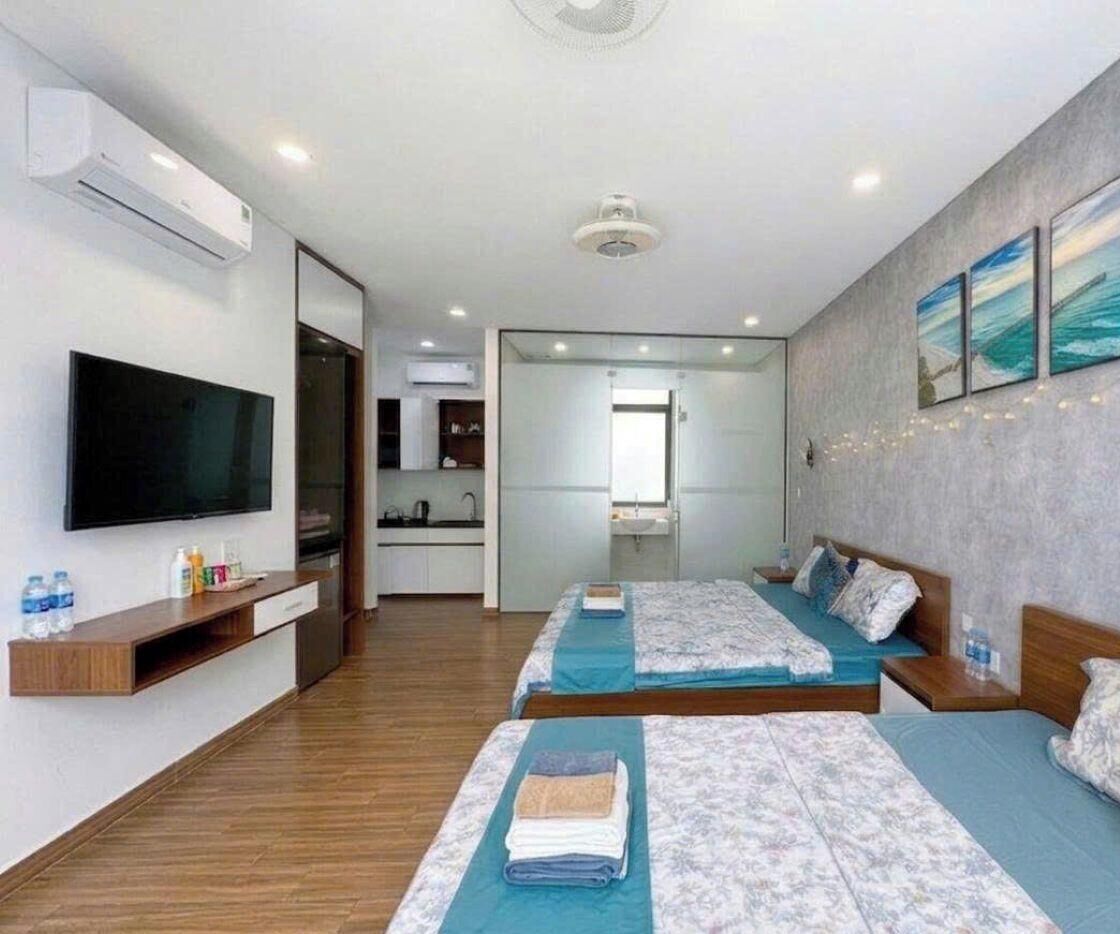Ein Hotelzimmer mit zwei Betten, einem Fernseher, einer Küchenzeile und einem Badezimmer.