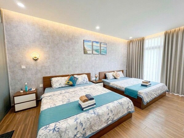 A hotel room with two beds, a nightstand, a wall-mounted light, and a window with curtains. - Ha Lan Homestay Grand World Phu Quoc (Phu Quoc)