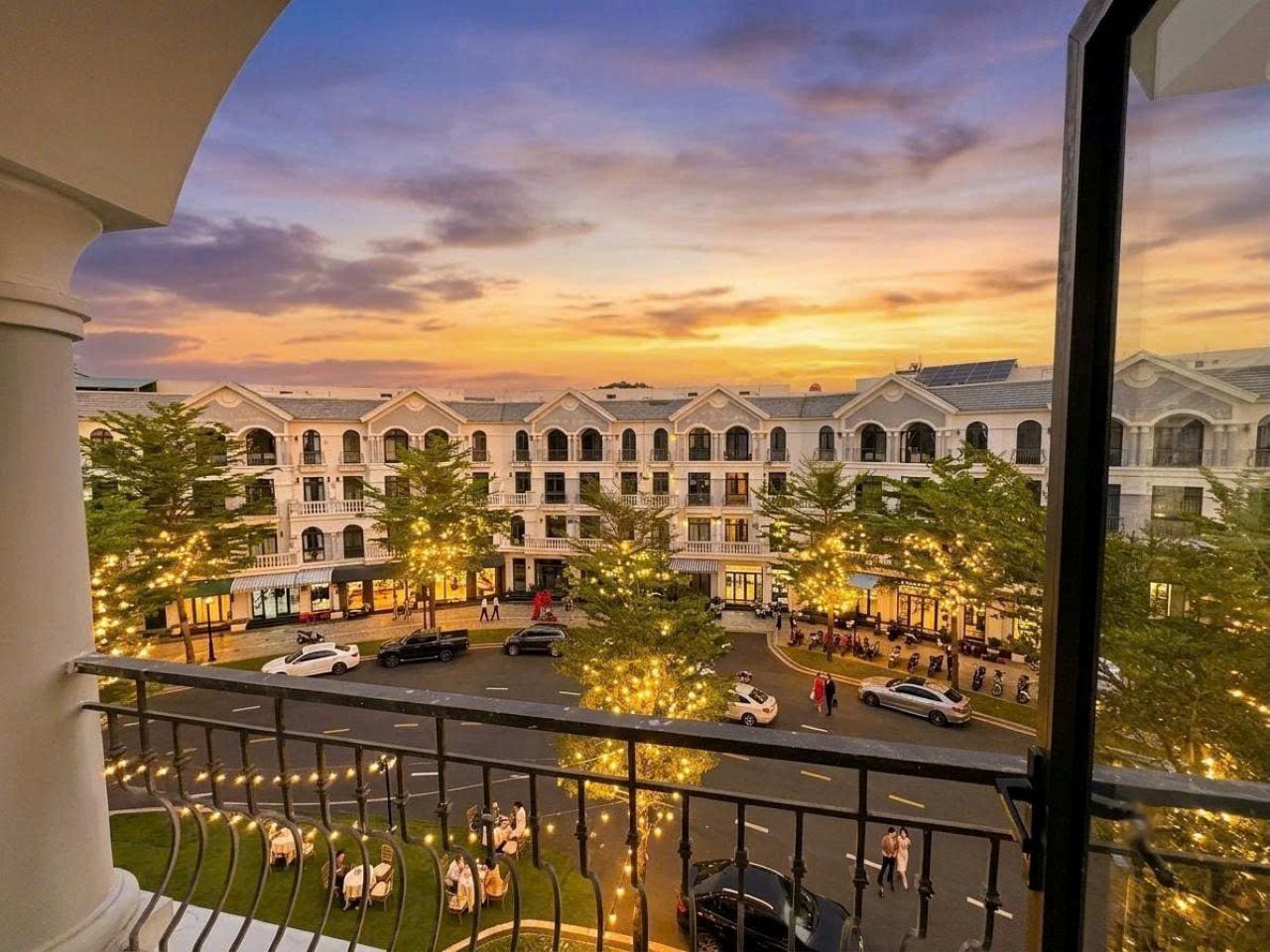 A hotel courtyard with a central open space, surrounded by buildings with arched windows and a balcony overlooking the area.