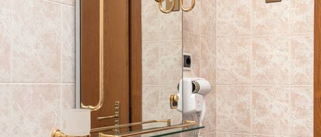 A bathroom with a mirror, a sink, and a hairdryer.