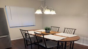 A dining area with a round table, four chairs, a chandelier, a refrigerator, and a window with blinds. - SUMMER TIME SPECIALS!
Enjoyable 2-bedroom condo with AC in vibrant Tempe. (Tempe)