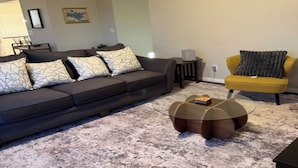 A living room with a dark sofa, patterned cushions, a glass coffee table, a yellow armchair, and a carpeted floor. - SUMMER TIME SPECIALS!
Enjoyable 2-bedroom condo with AC in vibrant Tempe. (Tempe)