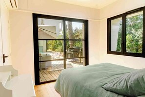 Ein Schlafzimmer mit einem Bett, einer Schiebetür zu einem Außenbereich und einem Fenster.