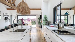 Cozinha moderna com ilha central, vigas de madeira e grandes janelas.
