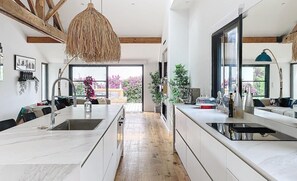 Eine moderne Küche mit einer zentralen Kochinsel, Holzbalken und großen Fenstern.