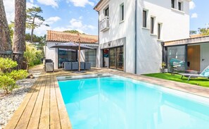 A swimming pool with a wooden deck, a white building with a tiled roof, and a grassy area. - Luxurious Villa Chiberta • Pool • 5 suites • Golf & Beach (Anglet)