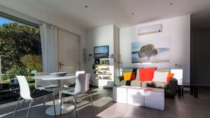 Un soggiorno moderno con zona pranzo, un divano con cuscini colorati, un tavolino da caffè e una libreria.