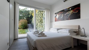 Una camera d'albergo moderna con un letto, una scrivania e vista sul verde.