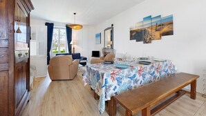 Uma sala de jantar com mesa posta para quatro pessoas, um banco de madeira e vista para o exterior.