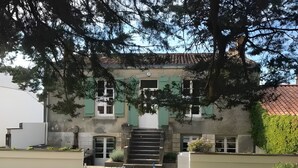 Uma área de refeições com mesas e cadeiras ao ar livre, uma escadaria que leva a um edifício com portaria verde e vista para a paisagem circundante.