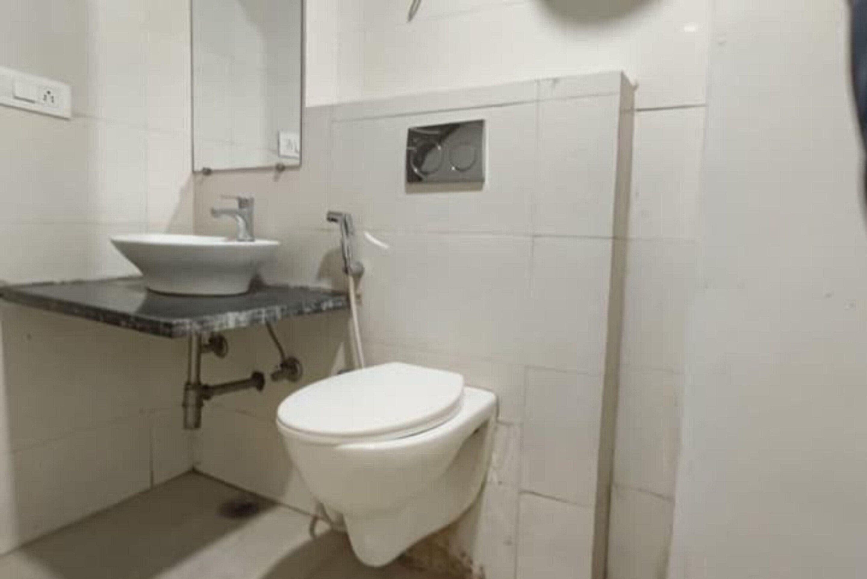 A small bathroom with a white sink, a toilet, and a mirror.