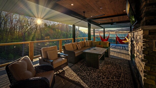 Un espace extérieur aménagé avec des meubles en osier, un tapis à motifs et une vue sur la forêt.