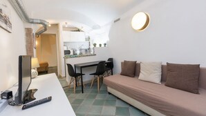 Een knus leefruimte met een bank, een eettafel met stoelen, een televisie en een keukenhoek.