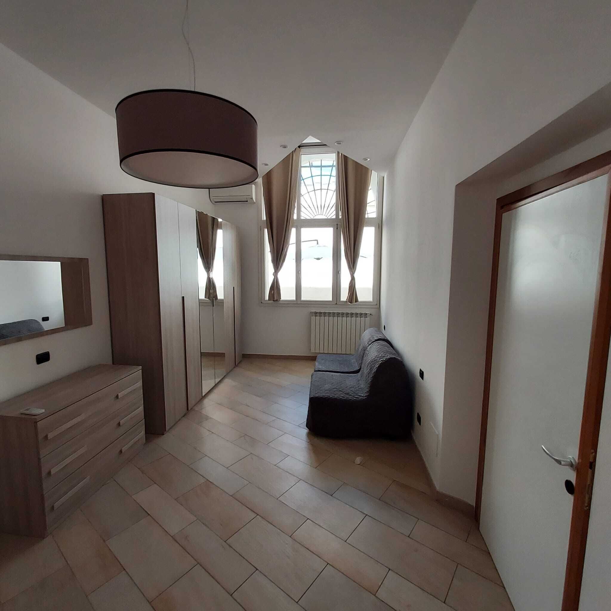 Ein Zimmer mit Kleiderschrank, einer Couch, einem Fernseher und einer Tür.