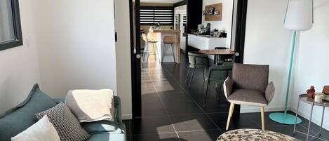 Un salon moderne avec un canapé, une table basse et une vue sur la cuisine.