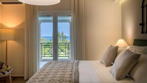 Ein Schlafzimmer mit Bett, Kissen, einer Lampe, Meerblick und einem Balkon.