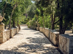 A stone pathway flanked by trees and stone walls, leading to a distant view. - Rivazzurra Luxury Villa, Villa (Lithakia)