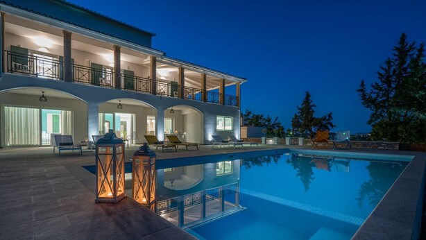 Ein moderner Poolbereich mit klarem Pool, Liegestühlen und einem großen Gebäude mit mehreren Balkonen.