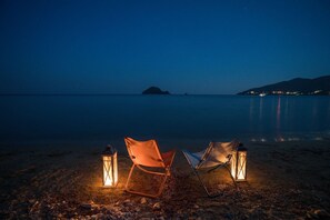A beach scene at night with two chairs and two lanterns. - Rivazzurra Luxury Villa, Villa (Lithakia)