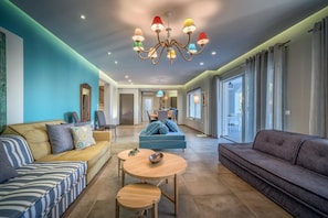A modern living room with a sofa, a dining table, and a chandelier. - Rivazzurra Luxury Villa, Villa (Lithakia)