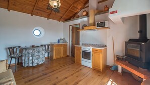 Una cocina acogedora con armarios de madera, estufa, microondas y comedor con mesa y sillas.