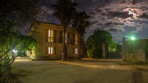 Un edificio de dos pisos con varias ventanas y una entrada protegida por una reja.