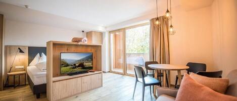 Ein modernes Wohnzimmer mit Flachbildfernseher, einer Couch, einem Esstisch und einem Stuhl.
